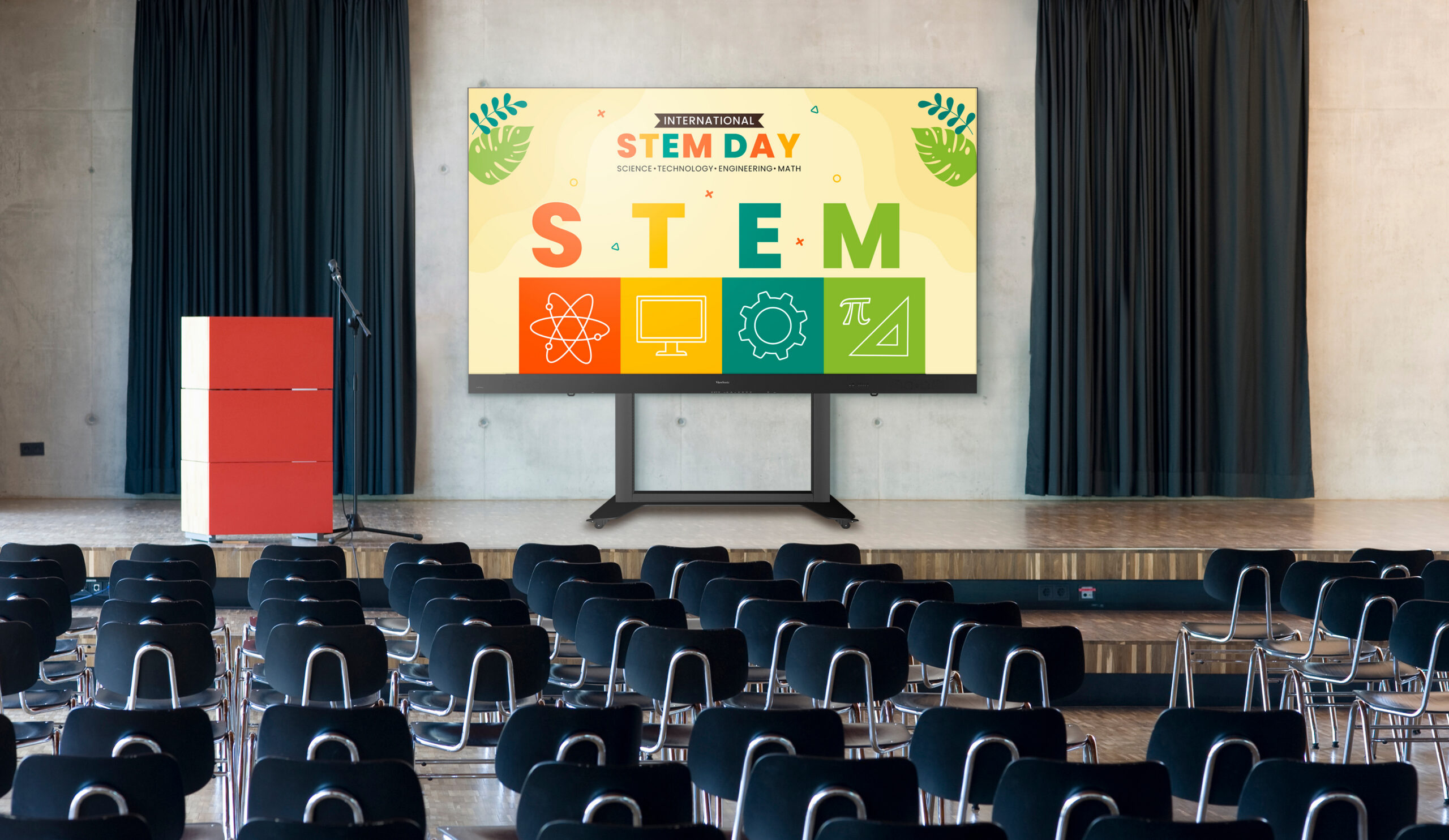 Lecture hall stage with a large colorful STEM Day poster on a screen, a red podium on the left, and empty rows of black chairs facing the screen.