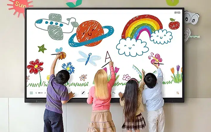 Four children draw on a large touchscreen whiteboard filled with colorful doodles—rainbow, sun, planet, flowers, and clouds in a classroom setting.