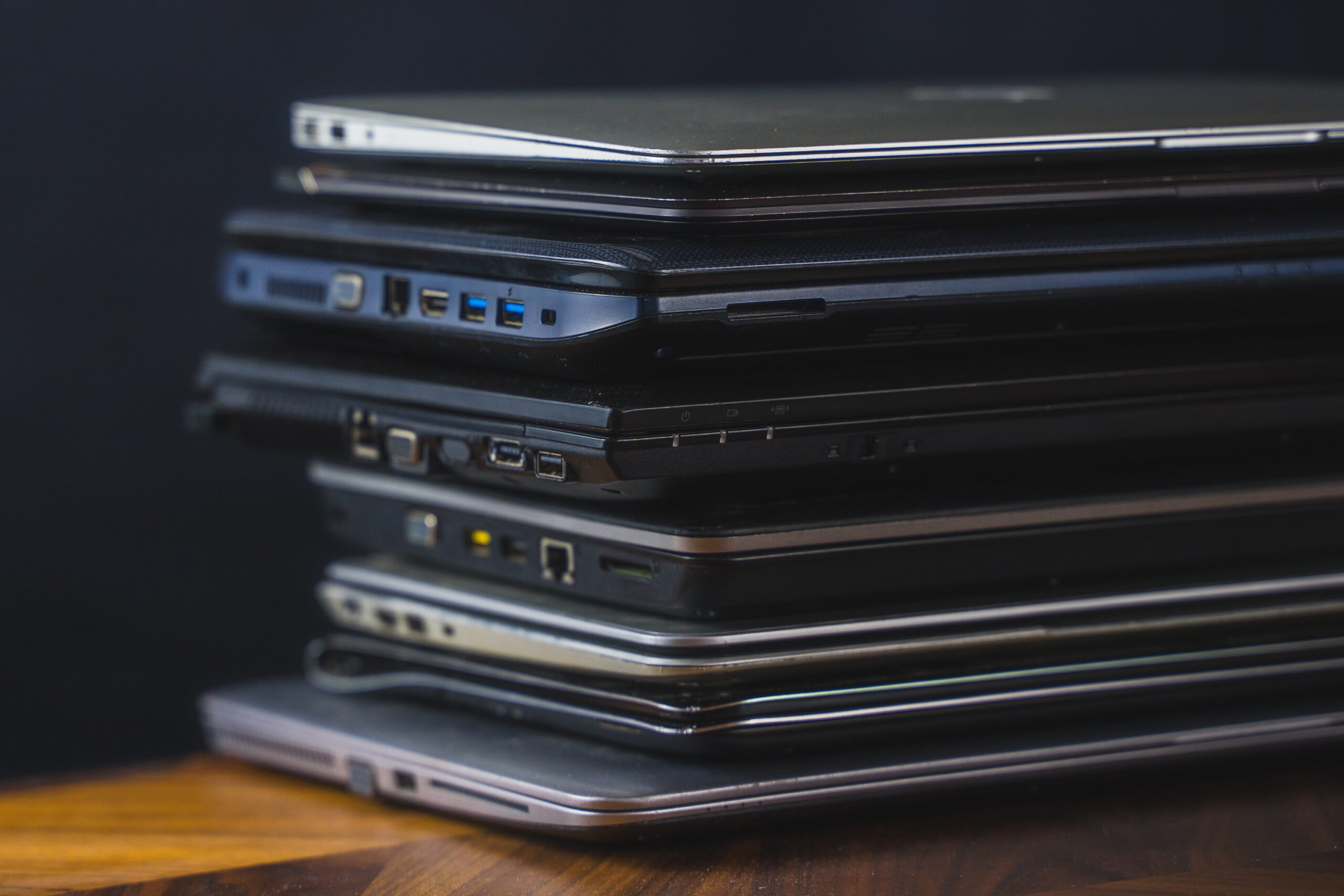 Close-up of a stack of laptops showing side ports (usb, hdmi, etc. ).