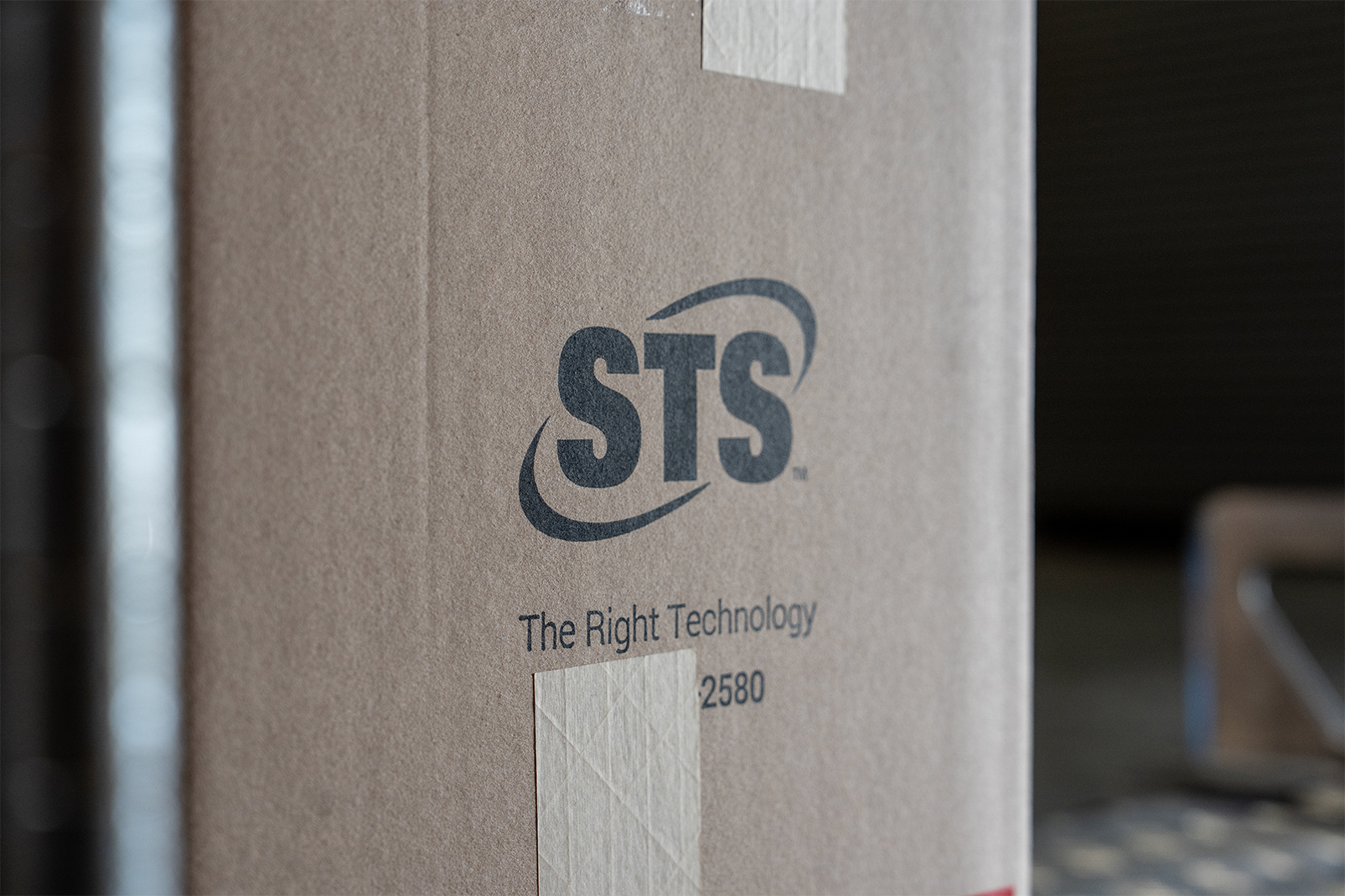 Cardboard box with the sts logo and the slogan 'the right technology' visible on the side.